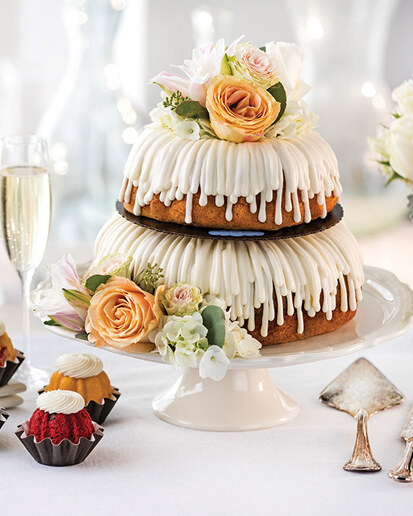 Tiered Bundt cake with white drizzle frosting and flowers by Nothing Bundt Cakes