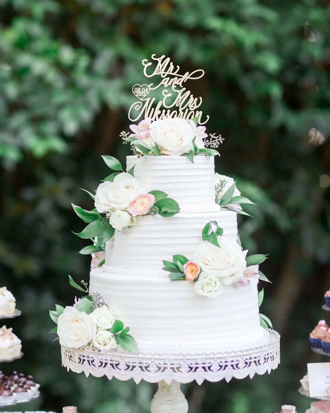 Three-tier white wedding cake with floral details by Sweet Kneads