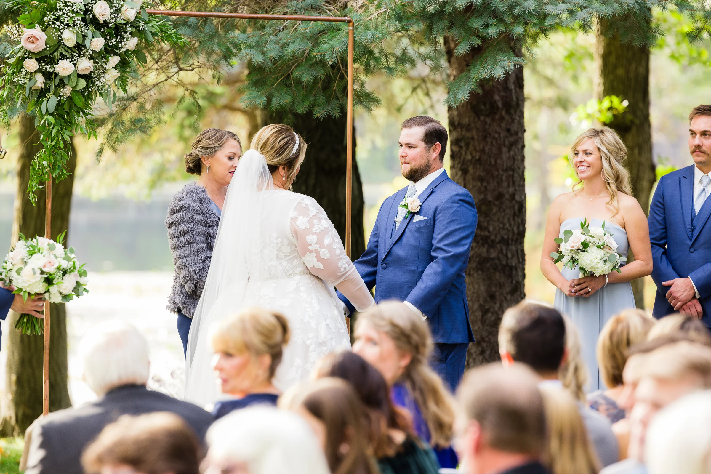 Outdoor ceremony beneath a copper floral arch in the gardens