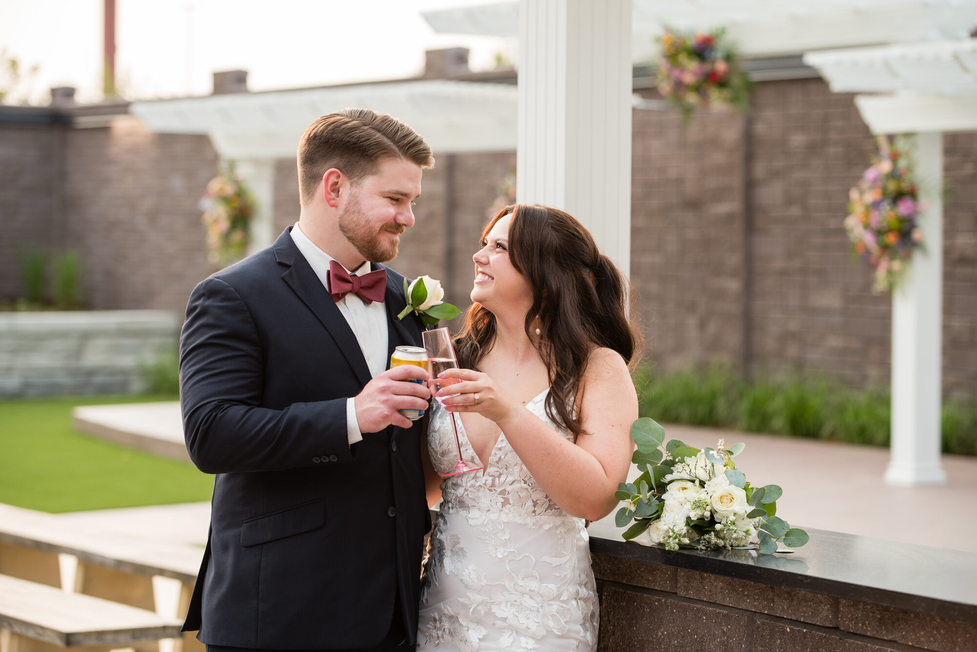 Bride and groom toast on the outdoor patio beside the pergola and floral arrangements at Royal Cliff, Eagan MN