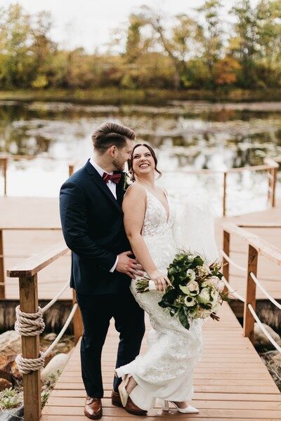 Bride laughing with her groom on the dock surrounded by autumn foliage at The Chart House, Lakeville MN