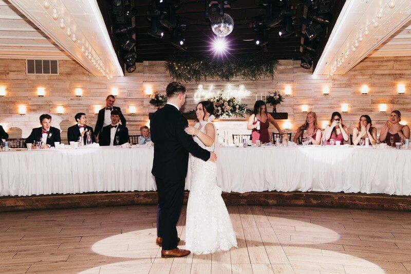 Couple dance under a disco ball as the wedding party watches from the head table at The Chart House, Lakeville MN