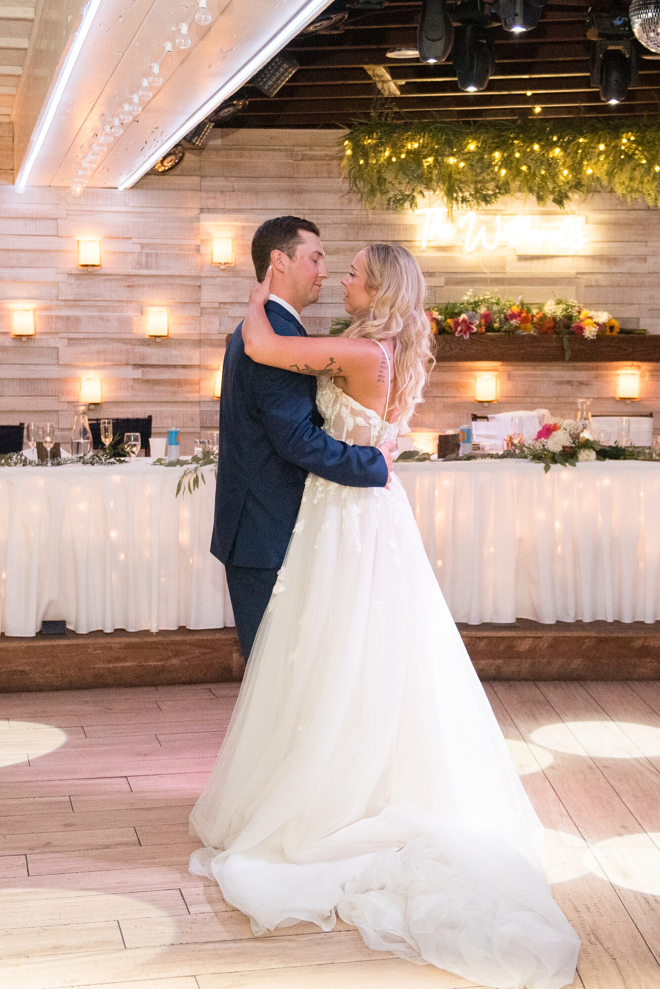 Bride and groom share their first dance in front of the head table and 'Mr & Mrs' sign at The Chart House in Lakeville, Minnesota