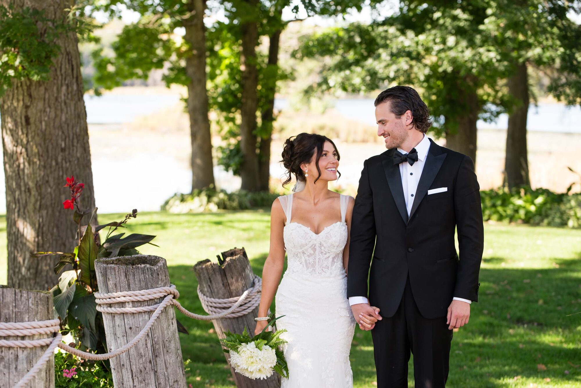 Bride and groom celebrating with their wedding party under a floral pergola at a Chart House outdoor ceremony