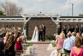 Outdoor garden ceremony viewed down the aisle as the couple stands beneath the pergola before seated guests at Royal Cliff, Eagan MN
