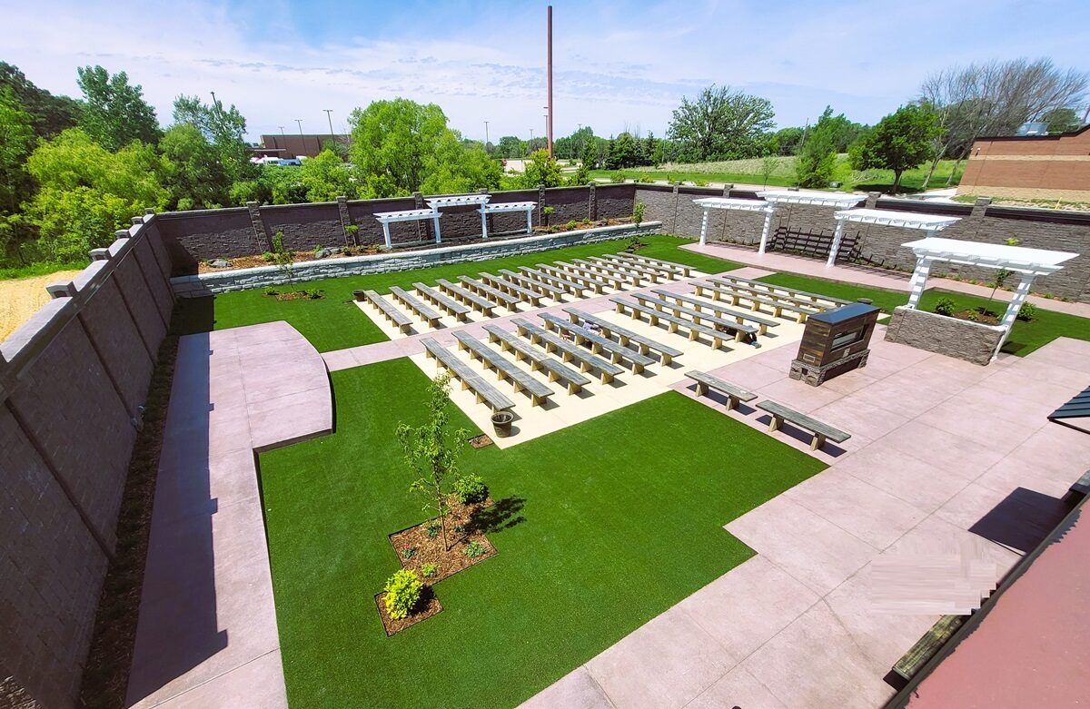 Aerial view of the walled outdoor ceremony garden with white pergolas, stone benches, and manicured lawn at Royal Cliff, Eagan MN
