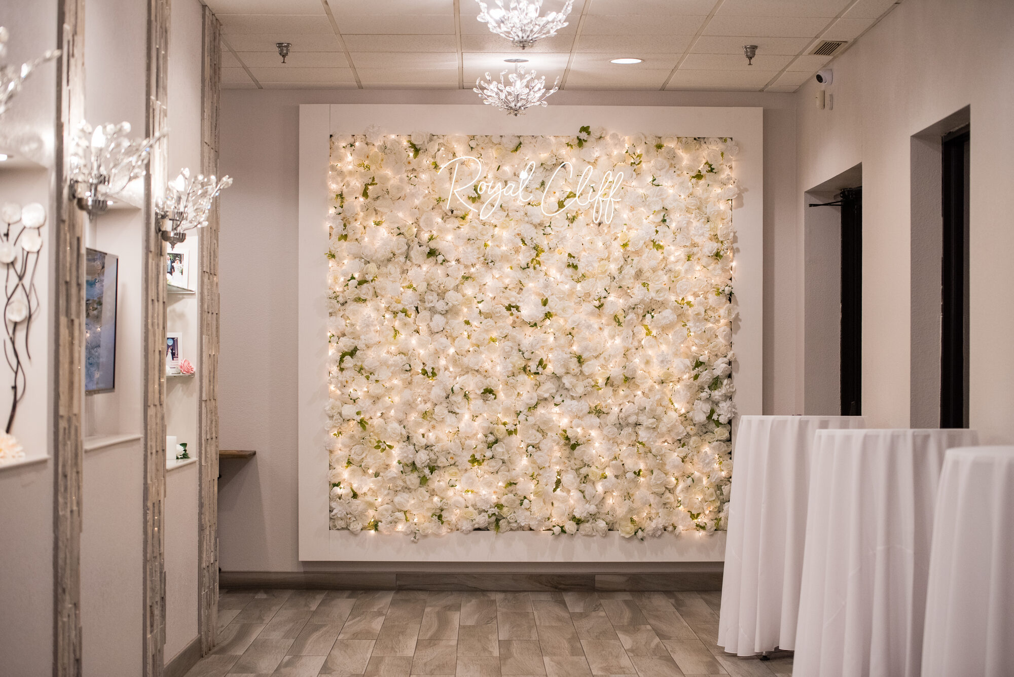 Welcome lobby with an illuminated white floral wall reading Royal Cliff and built-ins for the seating chart at Royal Cliff, Eagan MN